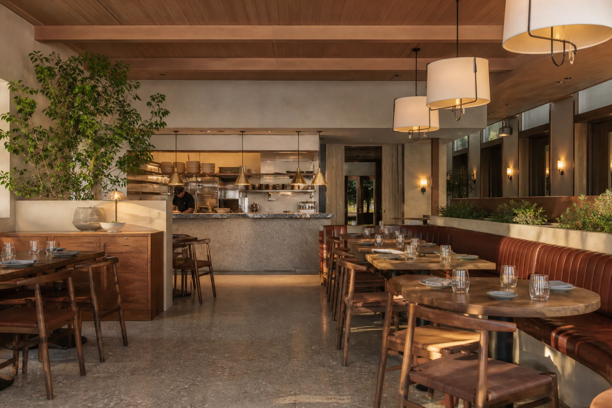 Contemporary restaurant interior with warm timber, plaster, stone, and integrated lighting