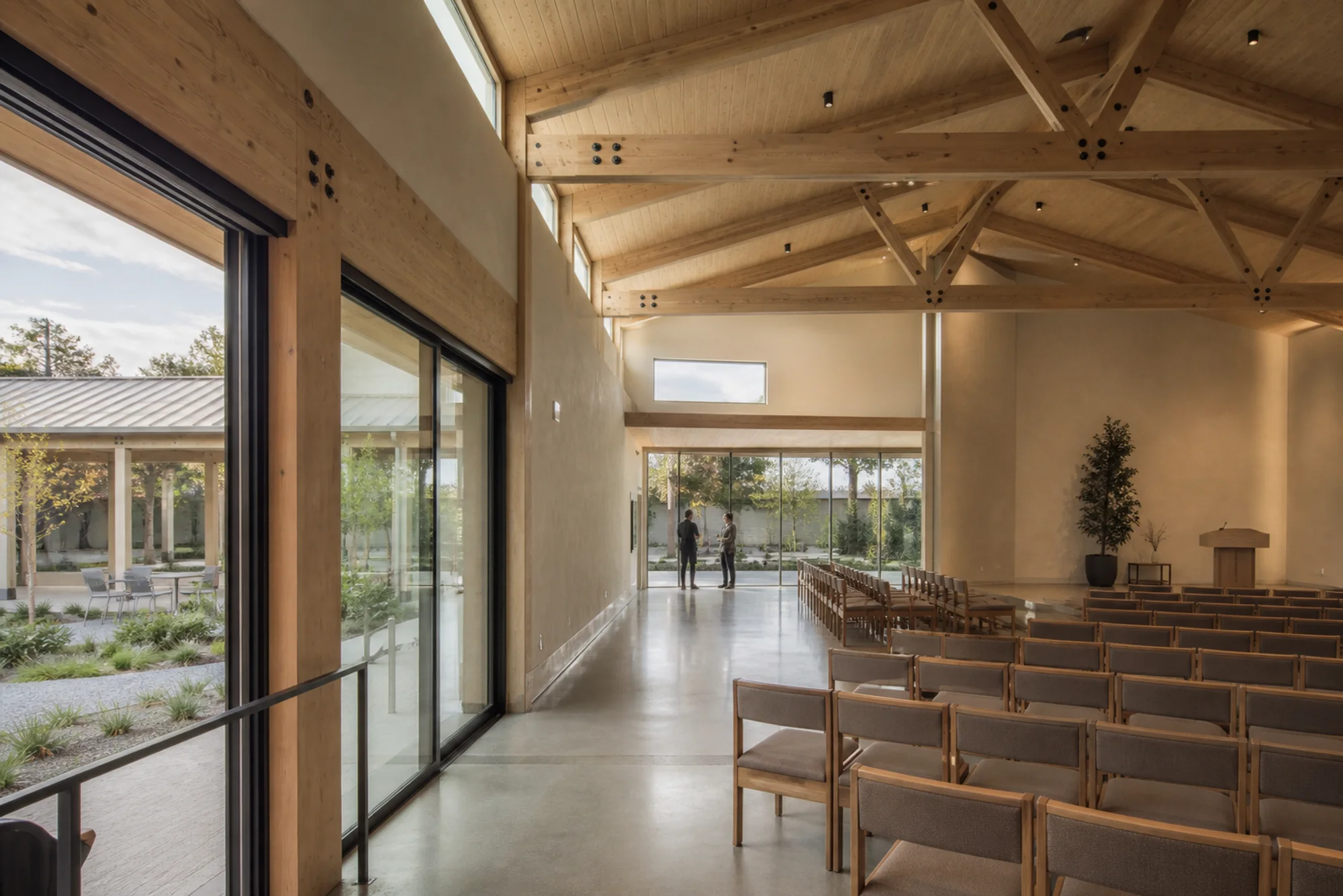 Timber community gathering hall opening to a quiet landscaped courtyard