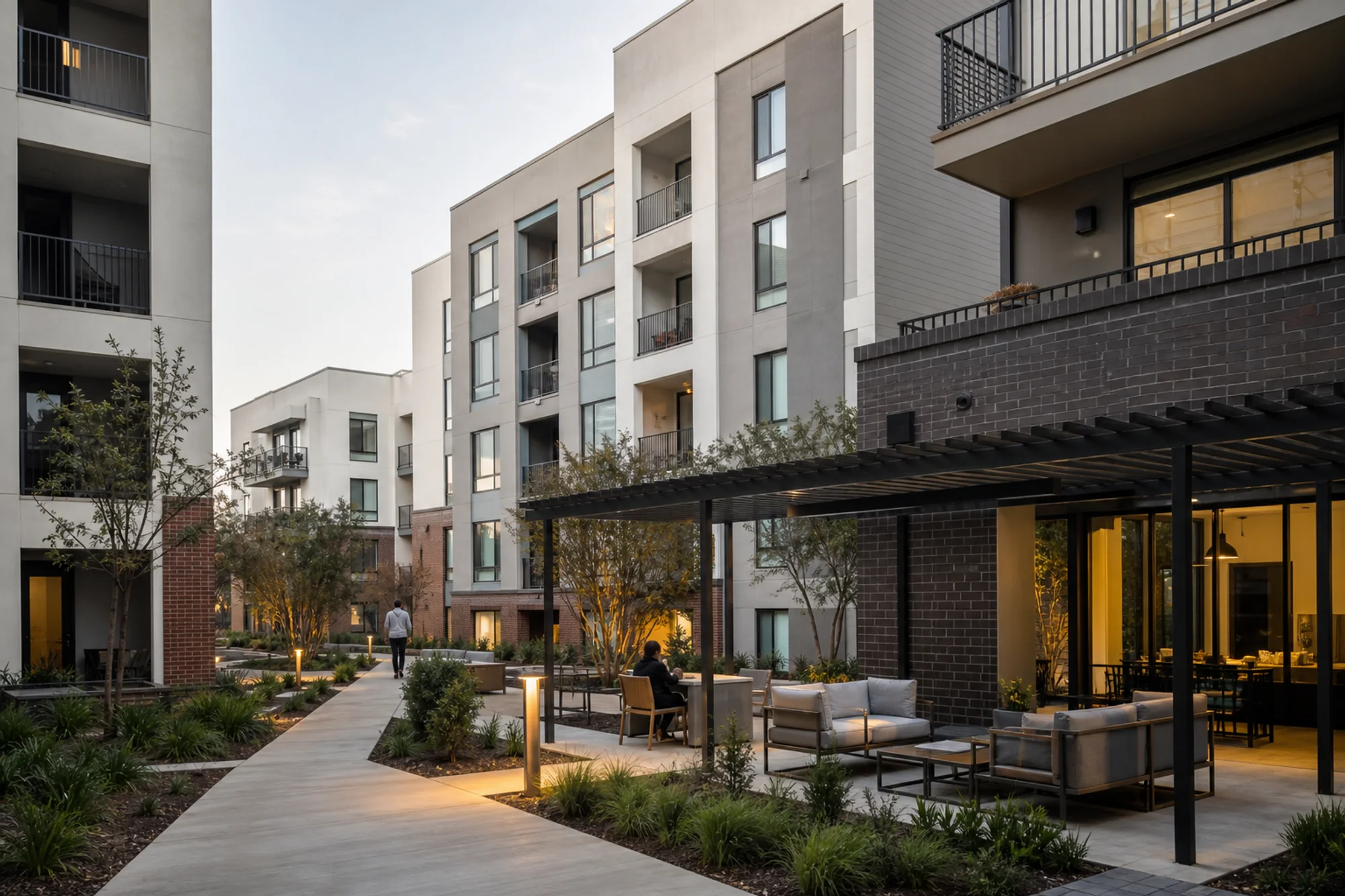 Multifamily residential courtyard with accessible paths, shared seating, and warm evening light